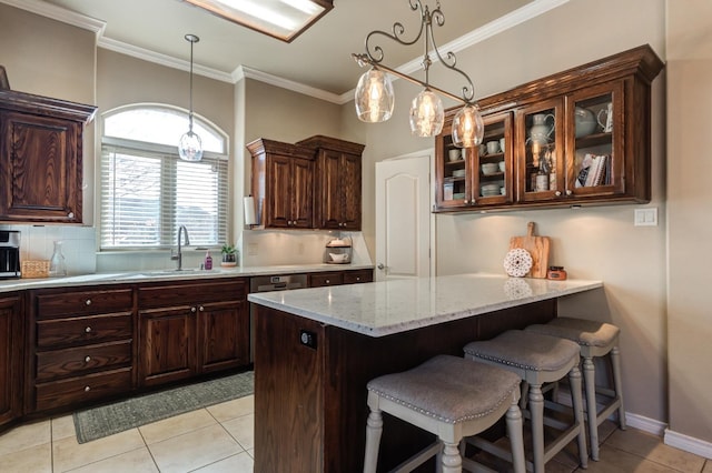 kitchen featuring sink, a breakfast bar area, light stone counters, dark brown cabinets, and backsplash