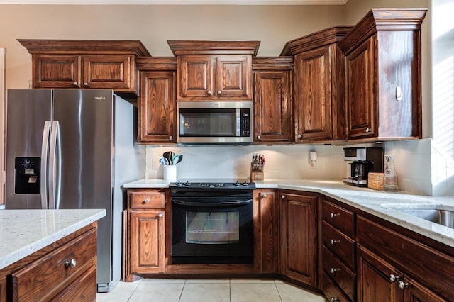 kitchen featuring stainless steel appliances, light stone countertops, and backsplash