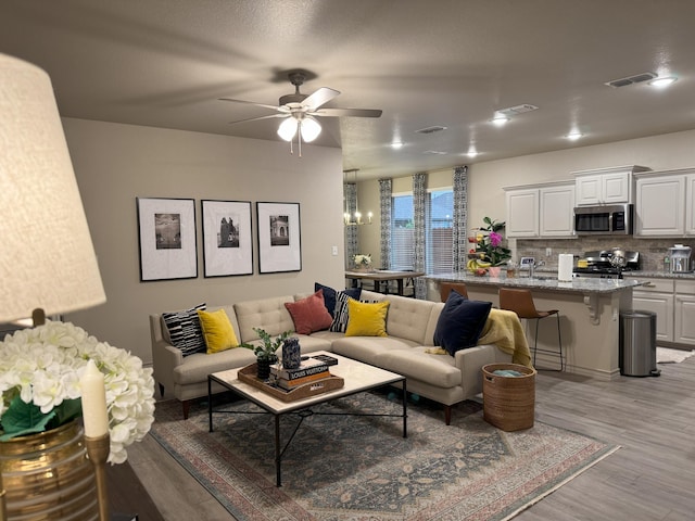 7101 22nd St, Lubbock, TX 79407 - living area featuring light wood finished floors, a ceiling fan, and a chandelier