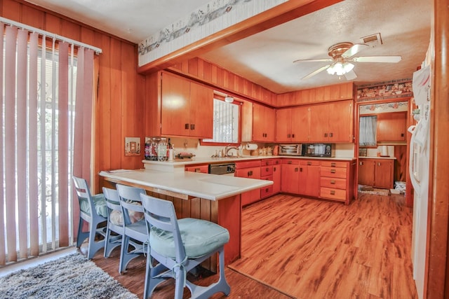 kitchen with a breakfast bar, kitchen peninsula, dishwasher, and light hardwood / wood-style flooring