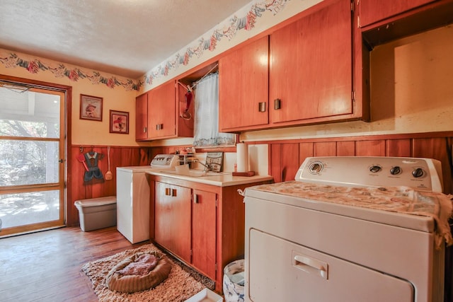 laundry area with washer / clothes dryer, light wood-type flooring, sink, and cabinets