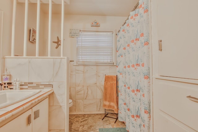 bathroom with vanity, tile walls, and toilet