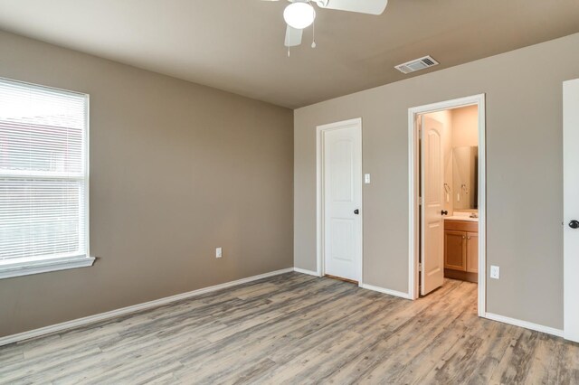 unfurnished bedroom featuring multiple windows, ceiling fan, light hardwood / wood-style floors, and ensuite bath