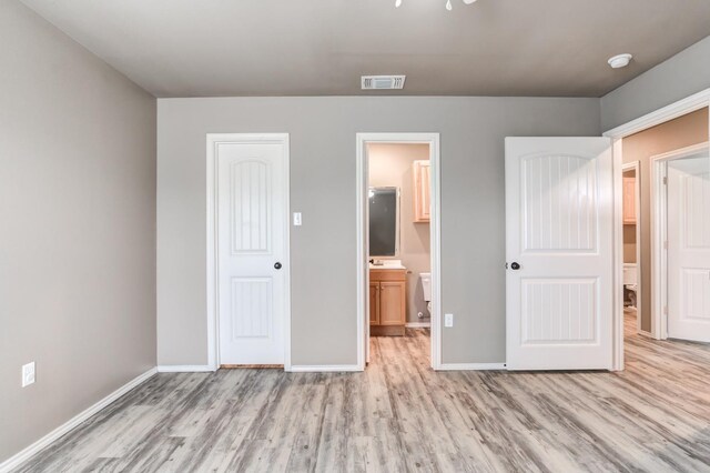 unfurnished bedroom featuring light hardwood / wood-style floors and ensuite bathroom