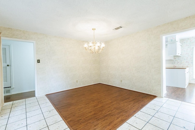 tiled spare room with a chandelier