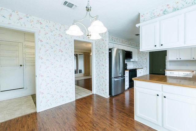 kitchen featuring white cabinetry, hanging light fixtures, range with electric cooktop, and stainless steel refrigerator