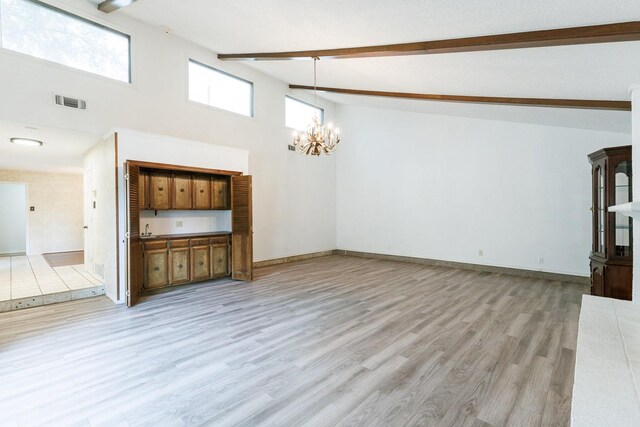 unfurnished living room featuring beam ceiling, light hardwood / wood-style flooring, high vaulted ceiling, and a chandelier