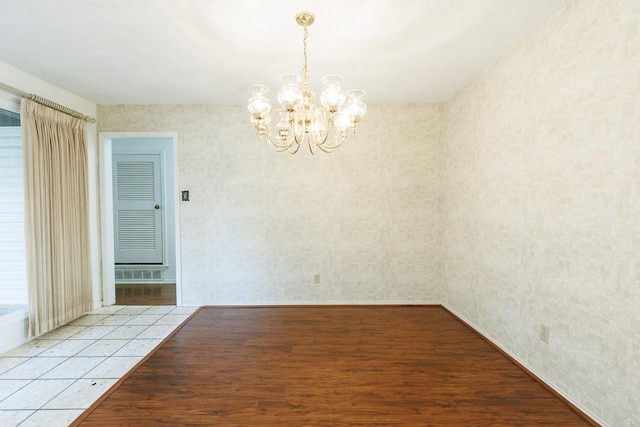 unfurnished room featuring a notable chandelier and light hardwood / wood-style floors