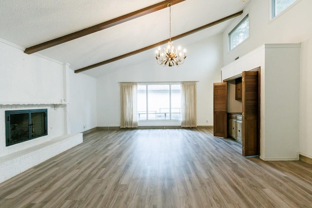 unfurnished living room featuring beamed ceiling, wood-type flooring, a fireplace, and a chandelier