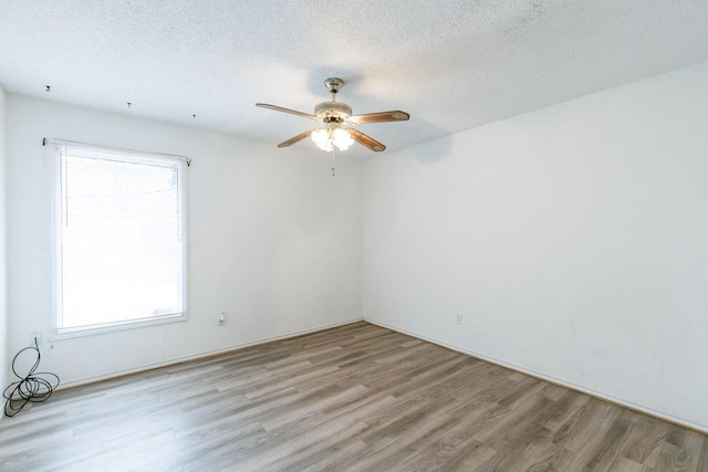 spare room featuring ceiling fan, a healthy amount of sunlight, a textured ceiling, and light hardwood / wood-style floors