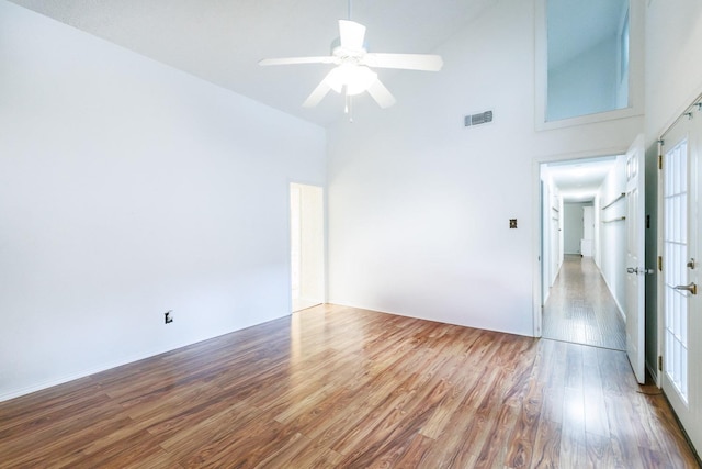 unfurnished room featuring a high ceiling, wood-type flooring, and ceiling fan