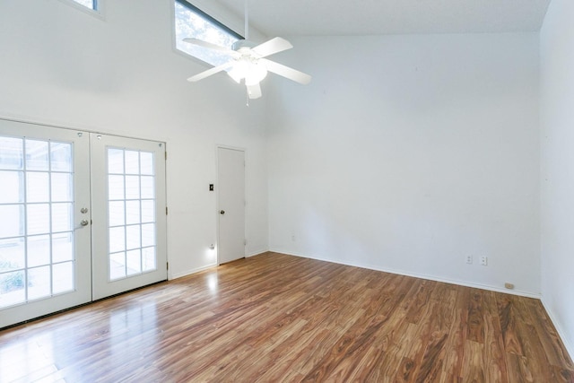 spare room featuring french doors, a healthy amount of sunlight, hardwood / wood-style floors, and a high ceiling