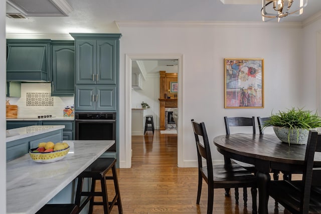 dining room with crown molding, wood finished floors, a chandelier, a fireplace, and baseboards