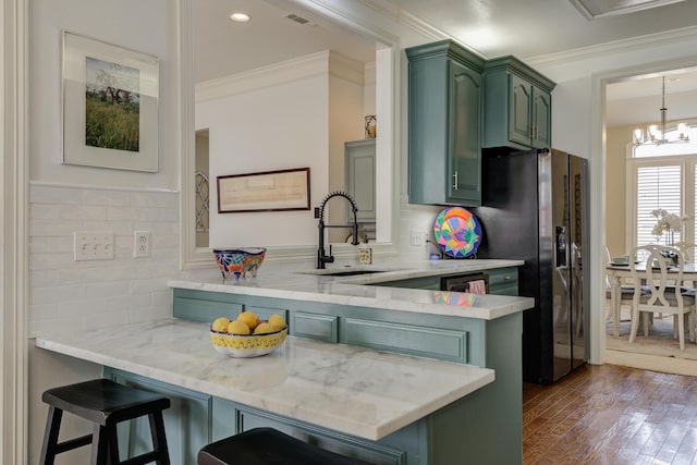 kitchen featuring a peninsula, a sink, green cabinets, and stainless steel fridge with ice dispenser