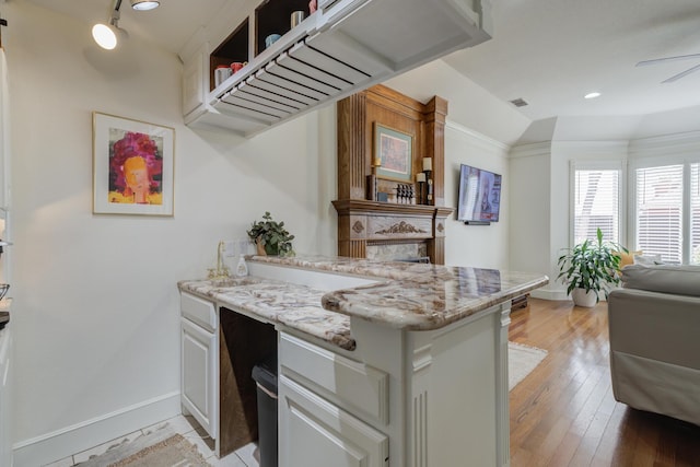 kitchen with light stone counters, a large fireplace, baseboards, a peninsula, and visible vents