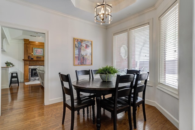 dining area featuring light wood-type flooring, a premium fireplace, an inviting chandelier, and ornamental molding