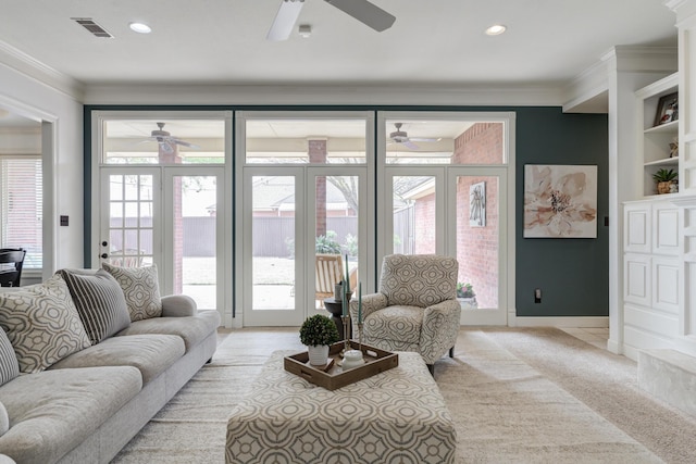 living room featuring ornamental molding, visible vents, ceiling fan, and a healthy amount of sunlight