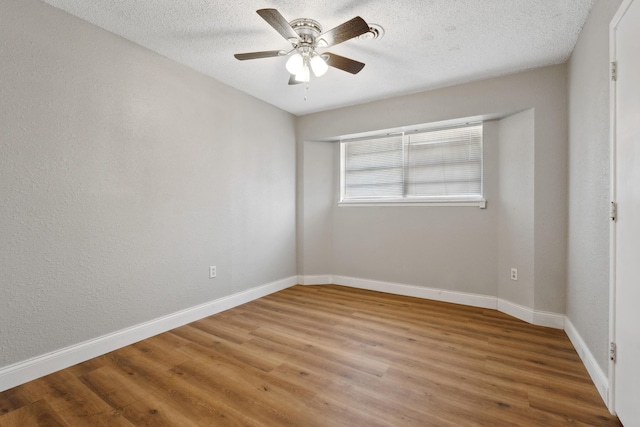 empty room featuring a textured ceiling, wood finished floors, a ceiling fan, and baseboards