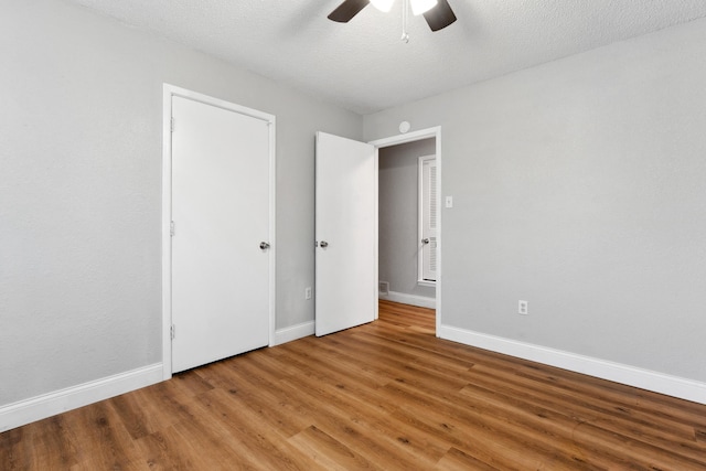 unfurnished bedroom featuring a textured ceiling, wood finished floors, a ceiling fan, and baseboards
