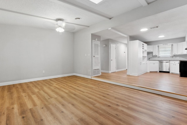 unfurnished living room featuring baseboards, visible vents, a ceiling fan, and light wood finished floors