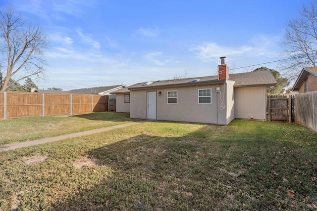 rear view of property with a lawn, a fenced backyard, and a chimney