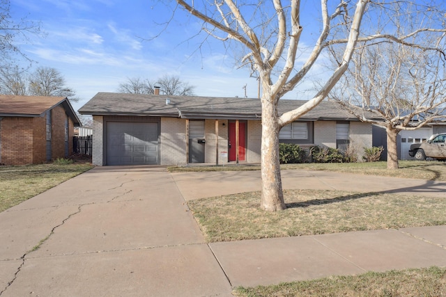 ranch-style house featuring concrete driveway, a front lawn, an attached garage, and brick siding