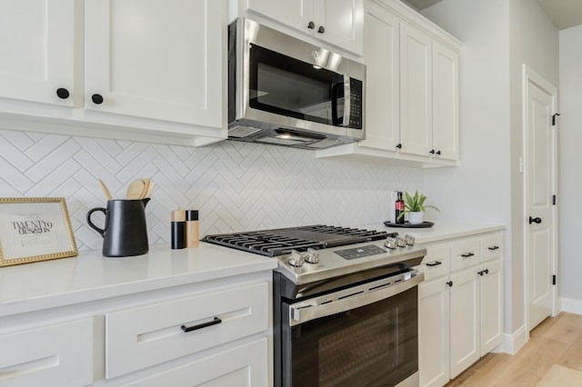 kitchen with stainless steel appliances, light wood-type flooring, white cabinets, and backsplash