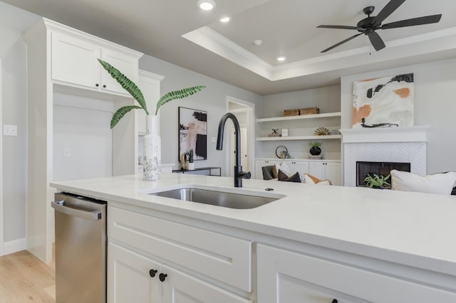 kitchen with sink, white cabinets, stainless steel dishwasher, a raised ceiling, and crown molding