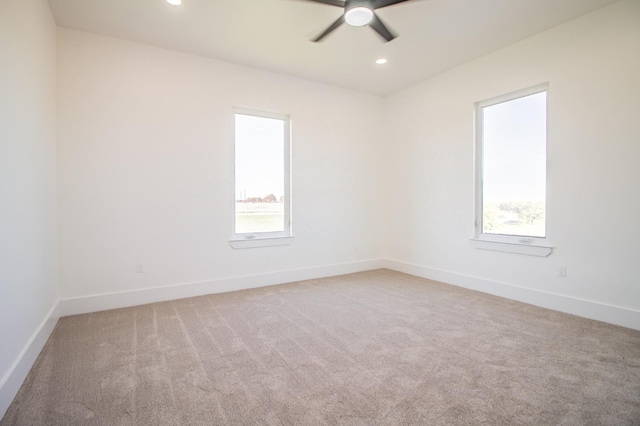 carpeted empty room with a wealth of natural light and ceiling fan