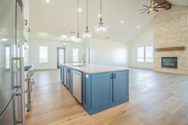 kitchen featuring high vaulted ceiling, premium appliances, a kitchen island with sink, pendant lighting, and light hardwood / wood-style floors