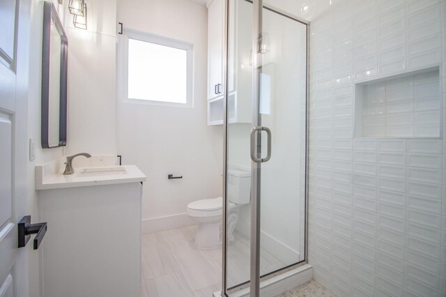 bathroom featuring vanity, a shower with shower door, and toilet