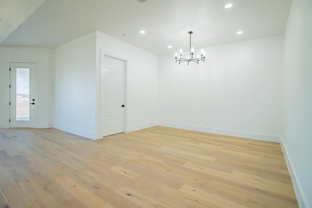 unfurnished room featuring a chandelier and light hardwood / wood-style floors