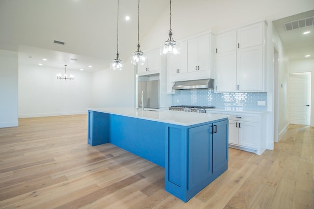 kitchen featuring white cabinetry, a kitchen island with sink, exhaust hood, and decorative light fixtures