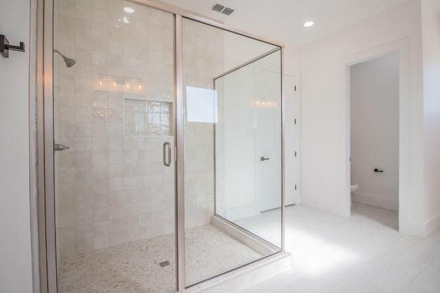 bathroom with a shower with door and toilet