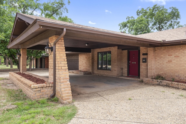 4635 30th St, Lubbock, TX 79410 - view of exterior entry with brick siding, a shingled roof, concrete driveway, and an attached carport
