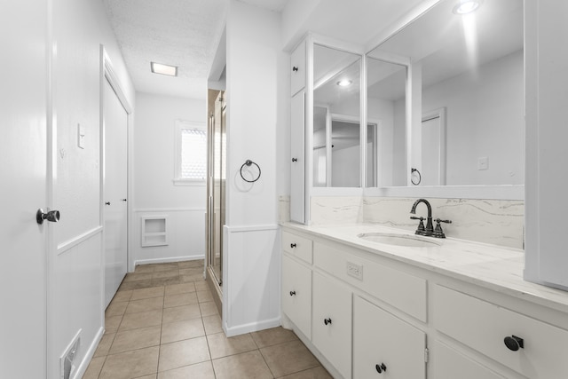 4635 30th St, Lubbock, TX 79410 - full bathroom featuring vanity, tile patterned flooring, a stall shower, and a textured ceiling