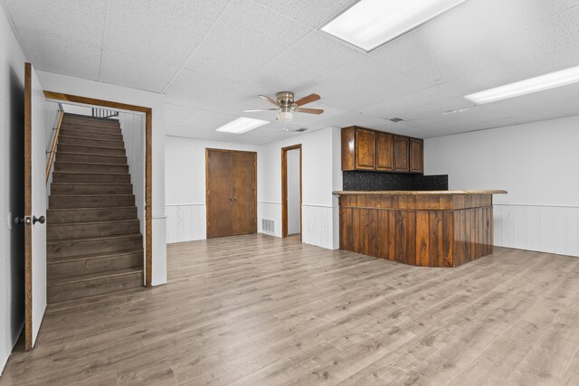 4635 30th St, Lubbock, TX 79410 - unfurnished living room with a ceiling fan, stairs, a wainscoted wall, light wood finished floors, and a bar