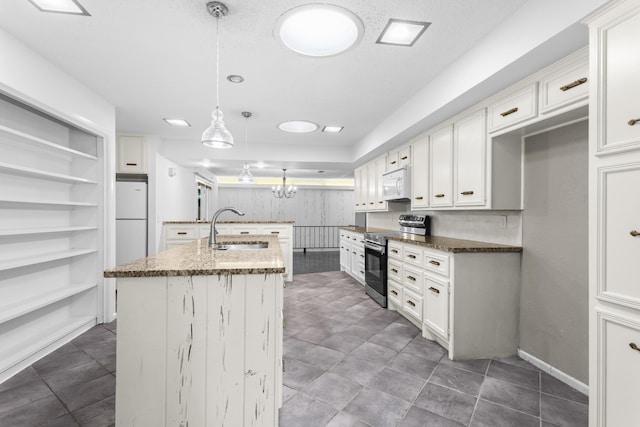 4635 30th St, Lubbock, TX 79410 - kitchen with white appliances, an island with sink, dark stone counters, hanging light fixtures, and white cabinets