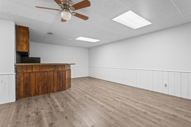 4635 30th St, Lubbock, TX 79410 - unfurnished living room featuring a drop ceiling, wainscoting, wood finished floors, a dry bar, and ceiling fan