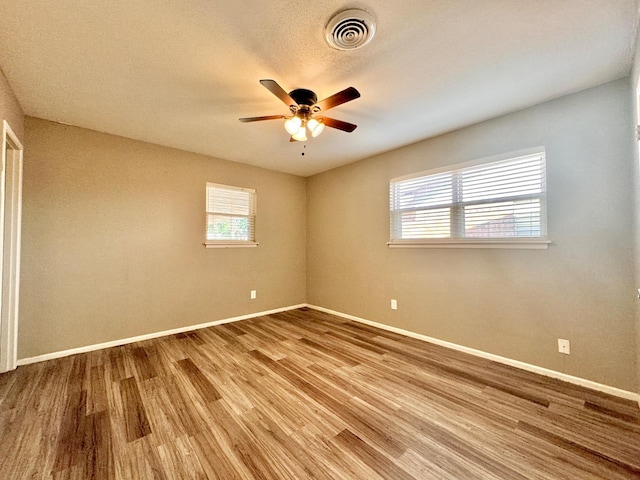 empty room with hardwood / wood-style flooring, a textured ceiling, and ceiling fan