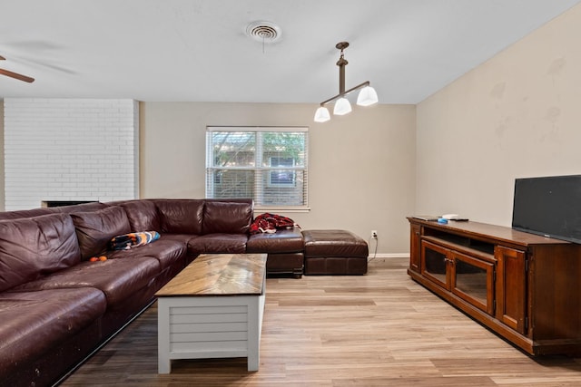 living room with ceiling fan, a fireplace, and light wood-type flooring