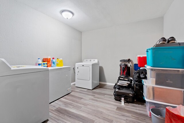 washroom featuring a textured ceiling, washing machine and clothes dryer, and light wood-type flooring