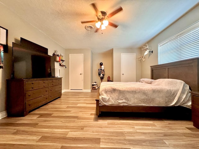 bedroom with ceiling fan, light hardwood / wood-style floors, and a textured ceiling