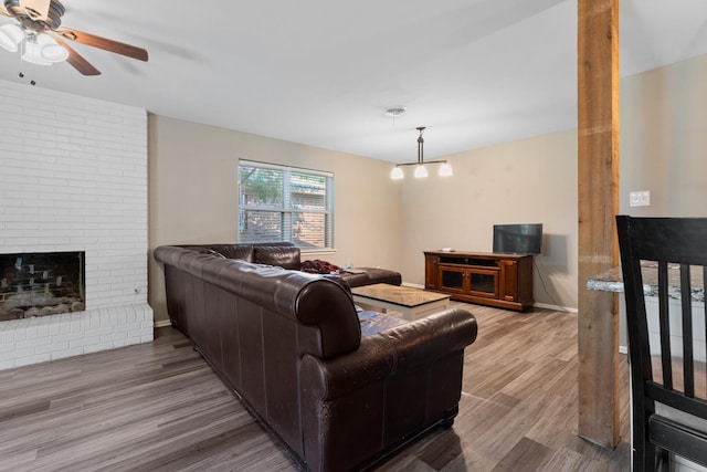 living room featuring hardwood / wood-style floors, a brick fireplace, and ceiling fan