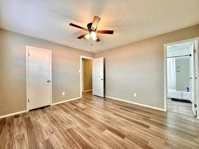 unfurnished bedroom with ceiling fan, ensuite bath, and light wood-type flooring