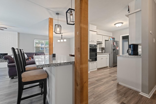 kitchen featuring white cabinetry, decorative light fixtures, stainless steel fridge with ice dispenser, and light hardwood / wood-style flooring