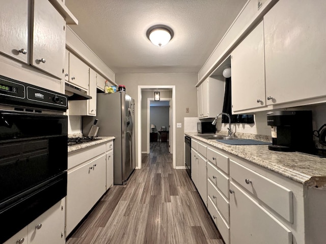 kitchen featuring appliances with stainless steel finishes, white cabinetry, sink, dark hardwood / wood-style flooring, and a textured ceiling