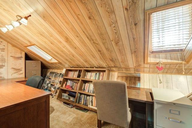 office space featuring light colored carpet, vaulted ceiling with skylight, wooden ceiling, and wooden walls