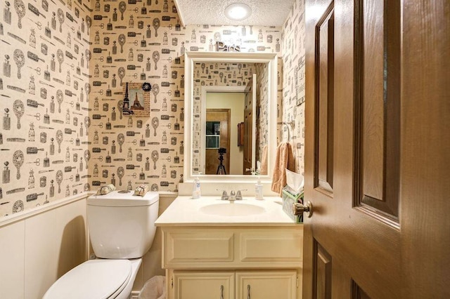 bathroom with vanity, toilet, and a textured ceiling