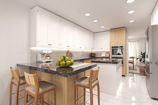 kitchen with appliances with stainless steel finishes, a breakfast bar, tasteful backsplash, white cabinetry, and kitchen peninsula